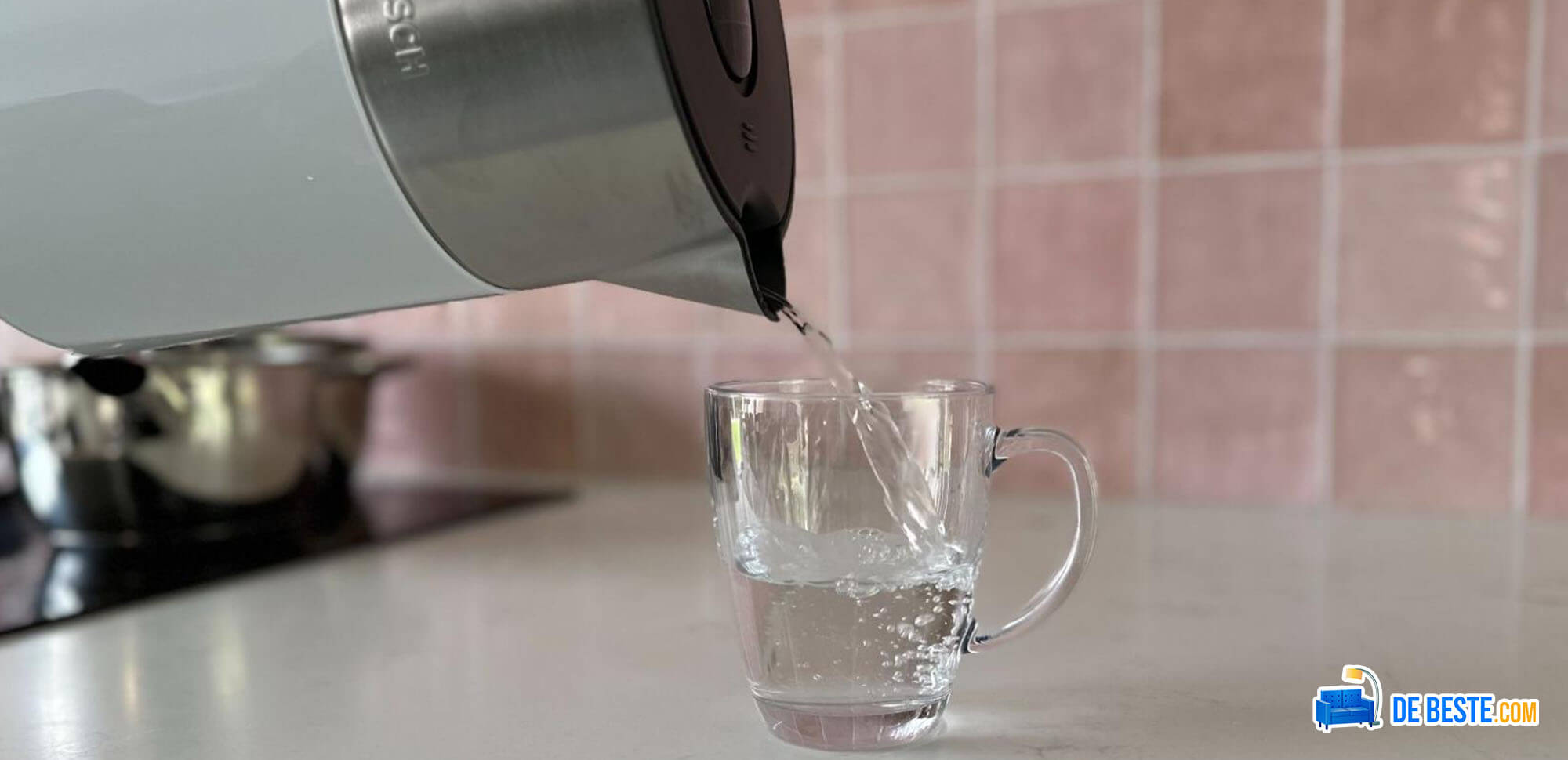 Een kopje water dat met een waterkoker in een glas wordt gegoten.