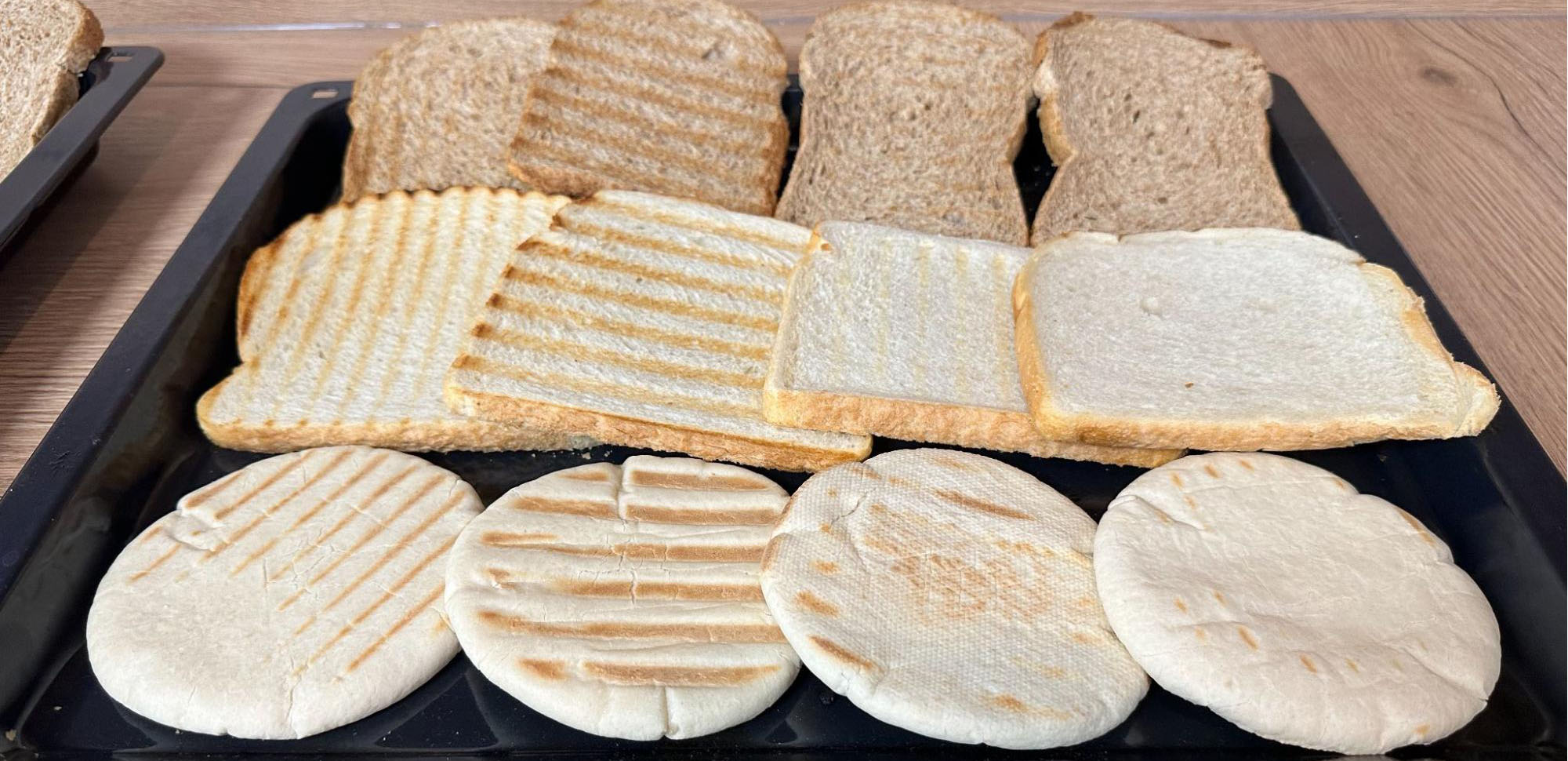 Op de foto zie je van de tosti-ijzers van Tefal GC241D12, JAP, Gadgy en Kitchenbrothers met een bruine boterham, een witte boterham en een pita broodje. Sommige hebben strepen op het brood, terwijl andere er wat bleker uitzien.