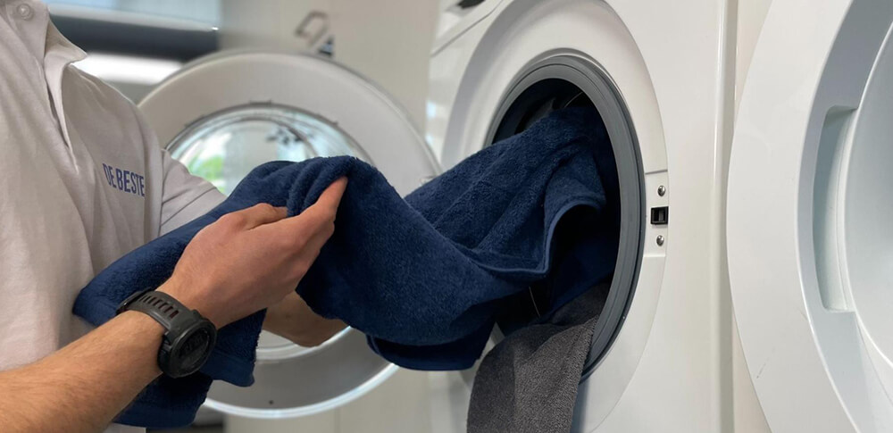 Jasper doet een handdoek in de wasmachine