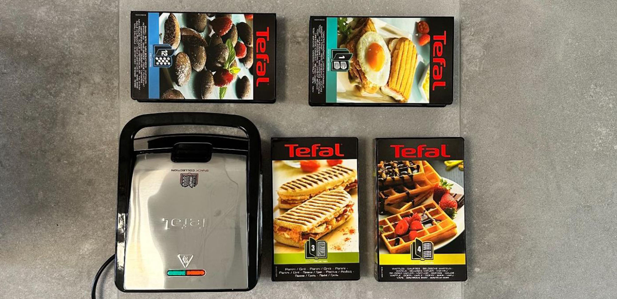 Op de foto zie je de Tefal Snack Collection SW854 D met ernaast 4 verschillende soorten platen. De platen kun je vervangen.