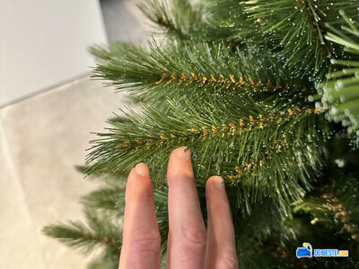 De hand van iemand raakt een kerstboom aan.