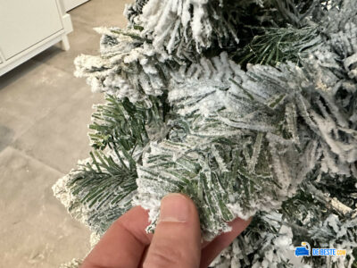 Een persoon houdt een klein stukje bevroren kerstboom vast.