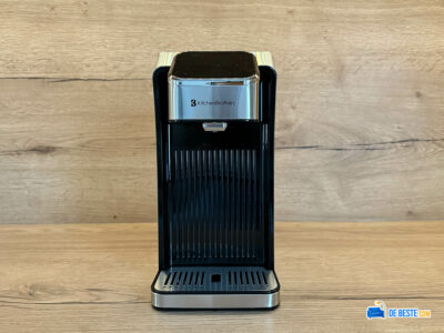 Een zwart en zilver koffiezetapparaat, zittend op een houten tafel.