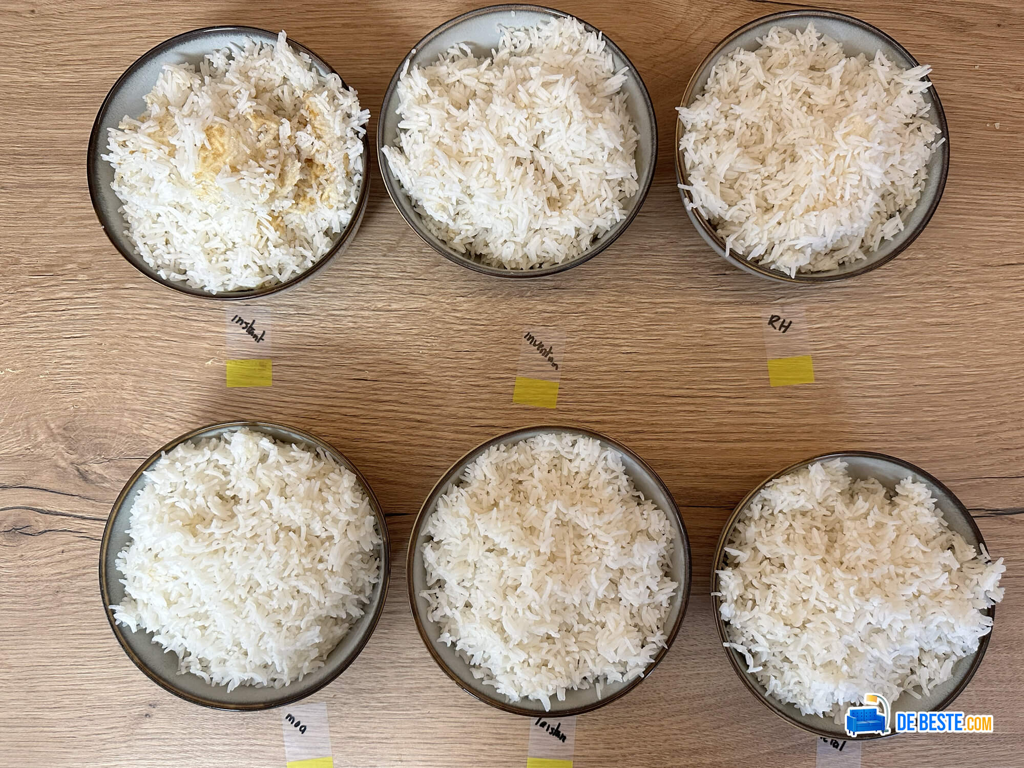 Op een houten tafel staan vijf kommen rijst opgesteld.