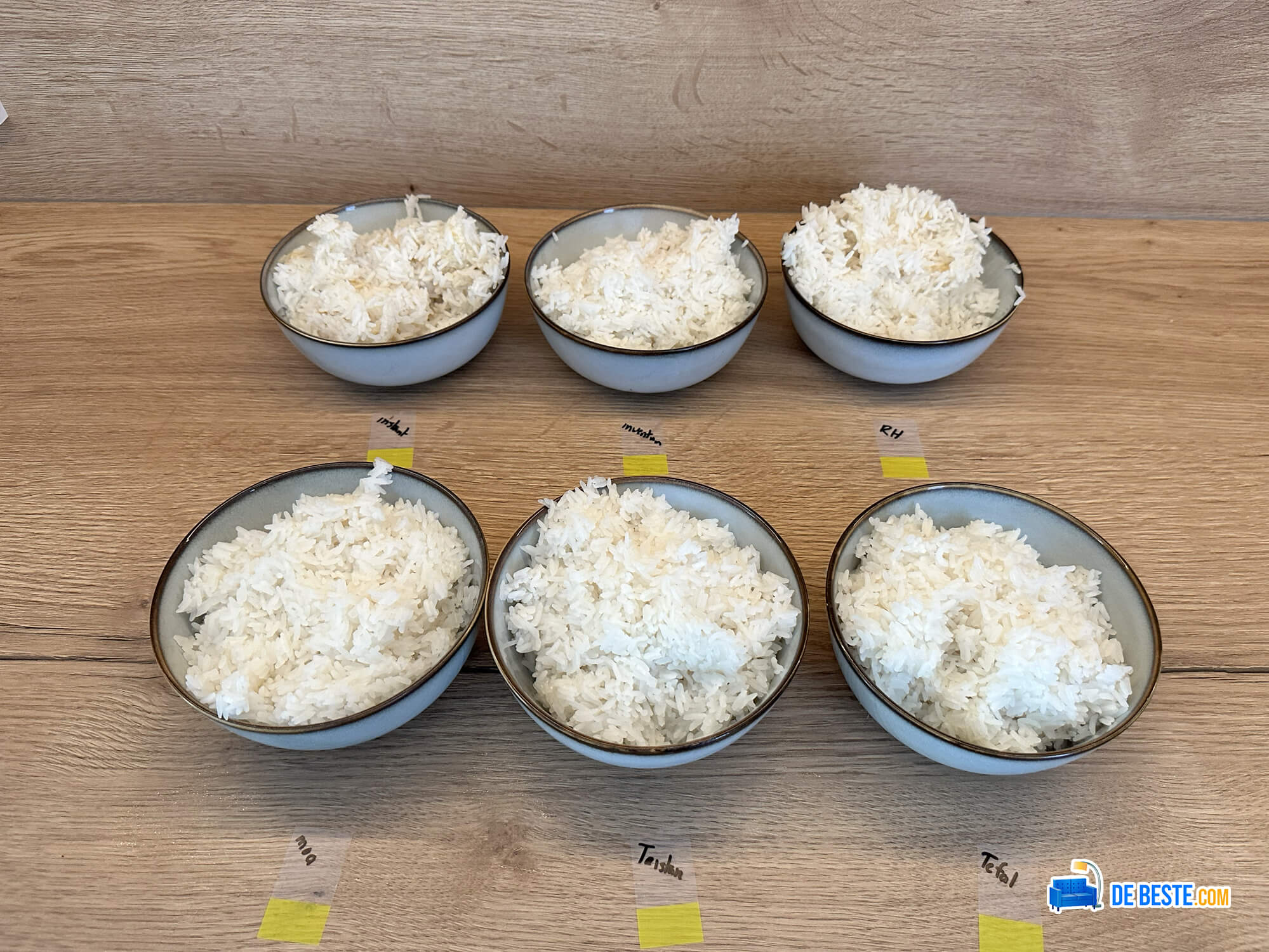 Vijf kommen rijst op een houten tafel.