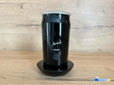 Een Philips Senseo-koffiezetapparaat met een glanzend zwarte afwerking, weergegeven op een houten oppervlak tegen een houten achtergrond.